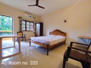 1 dormitorio con cama, mesa y ventana en Indraprasth Palolem Hill, en Palolem