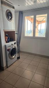 een wasruimte met een wasmachine en een raam bij Logement au calme, avec vue dégagée in Ardoix
