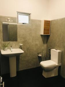 a bathroom with a sink and a toilet and a window at Beacon in Hikkaduwa