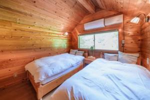 two beds in a log cabin bedroom with a window at Mori no Kuni - Vacation STAY 03921v in Ōma