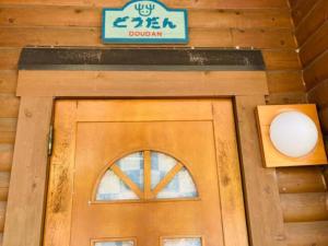 eine Tür zu einer Holzhütte mit einem Schild darüber in der Unterkunft Mori no Kuni - Vacation STAY 03967v in Ōma