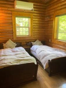 two beds in a room with wooden walls and windows at Mori no Kuni - Vacation STAY 03790v in Ōma