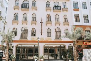 a large white building with windows and palm trees at Golden Sea Hotel in Ha Long