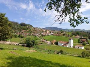 een klein dorpje op een heuvel met een groen veld bij Finca La Viñona. Casa rural con finca en San Román de Candamo in Candamin