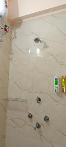 een badkamer met een witte marmeren muur met vier kleppen bij New Hindusthan Hotel in Siliguri
