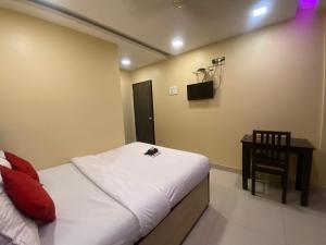 a bedroom with a bed and a table and a chair at Hotel Royal Grand - Near Mumbai International Airport in Mumbai
