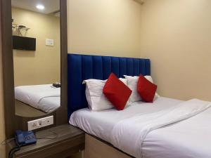 una camera con 2 letti con cuscini rossi e specchio di Hotel Royal Grand - Near Mumbai International Airport a Mumbai