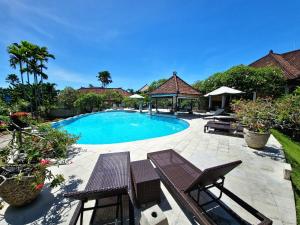 a swimming pool in a yard with chairs and avisor at Nipuri Resort and Villas Seminyak by Kamara in Seminyak