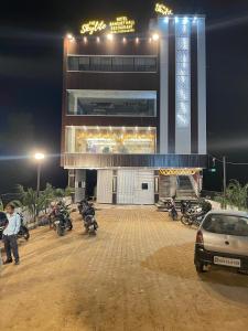 Ara的住宿－THE SKYLITE HOTEL & BANQUET，一座有摩托车的建筑,在晚上停在它前面