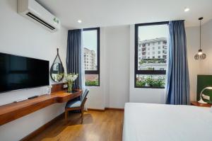 1 dormitorio con 1 cama y escritorio con TV en 22Land Classic Suites, en Hanói