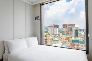 Un dormitorio con una ventana con vista a una ciudad. en Urbanstay Myeongdong, en Seúl