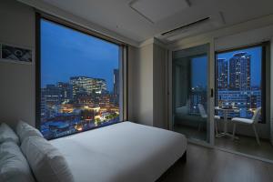1 dormitorio con ventana grande con vistas al perfil urbano en Urbanstay Myeongdong, en Seúl