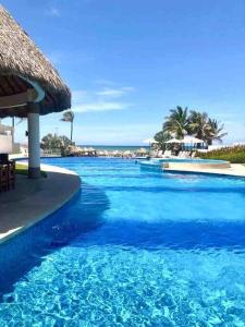 uma grande piscina azul com um guarda-chuva de palha em Hermoso Apartamento con club de playa em Acapulco
