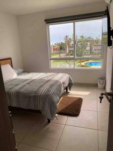a bedroom with a bed and a large window at Hermoso Apartamento con club de playa in Acapulco