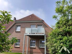 Una casa de ladrillo con un balcón en el lateral. en Balkonwohnung Norderney, en Hooksiel