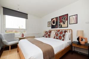1 dormitorio con 1 cama grande y 1 silla en The Kennington Park Crib - Lovely 2BDR Flat with Garden, en Londres
