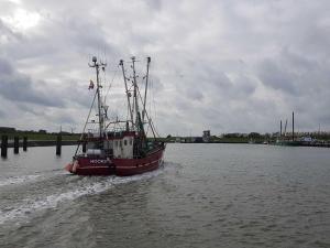 a red and white boat in the water at Balkonwohnung Leuchtturm in Hooksiel