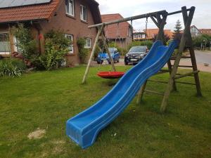 a playground with a blue slide in a yard at Balkonwohnung Roter Sand in Hooksiel