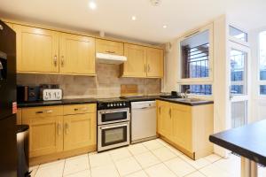 cocina con armarios de madera y horno con fogones en The Kennington Park Crib - Lovely 2BDR Flat with Garden, en Londres