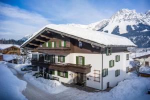 a house covered in snow with a mountain in the background at Haus Alpin in Ellmau