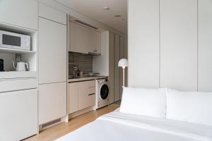 Un dormitorio blanco con una cama y una cocina. en Urbanstay Myeongdong, en Seúl