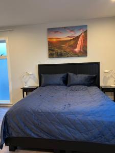 a bedroom with a blue bed with a painting on the wall at Nyibaer studio apartment in Selfoss