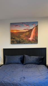 a bedroom with a bed with a painting on the wall at Nyibaer studio apartment in Selfoss
