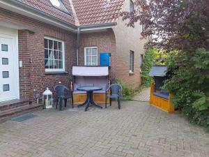 a patio with a table and chairs in front of a building at Terrassenwohnung Baltrum in Hooksiel