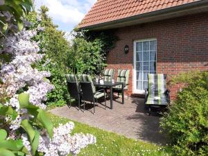 un patio con mesa y sillas frente a una casa en Terrassenwohnung Langeoog, en Hooksiel