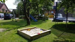 un arenero en el césped junto a un árbol en Terrassenwohnung Strandlust, en Hooksiel