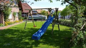 a playground with a blue slide in a yard at Terrassenwohnung Wangerooge in Hooksiel