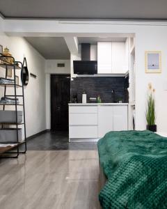una cucina con armadi bianchi e un letto verde in una camera di Best Studio Central a Hunedoara