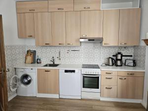 - une cuisine avec des placards en bois et un lave-vaisselle blanc dans l'établissement Ferienhaus Birnberg, à Leogang