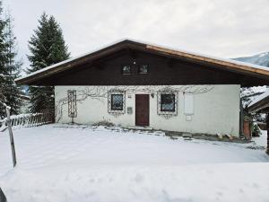 une maison avec de la neige devant elle dans l'établissement Ferienhaus Birnberg, à Leogang