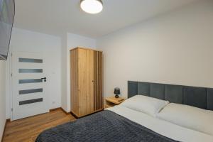 ein Schlafzimmer mit einem großen Bett und einem Holzschrank in der Unterkunft Vip Apartamenty Niecia z klimatyzacja in Rzeszów