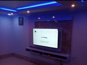 a large screen tv in a room with purple lights at Luxurious B in Lagos