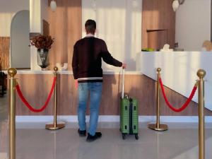 Mężczyzna wyciąga zieloną walizkę przy ladzie. w obiekcie فندق ارجان بارك العزيزية Arjan Park Hotel w Rijadzie