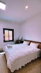 a bedroom with a large white bed with a window at Wooden House on lake,city center in Luang Prabang