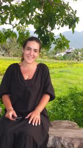 une femme assise sur un journal avec un téléphone portable dans l'établissement The Daun Puntik HomeStay, à Pawenang