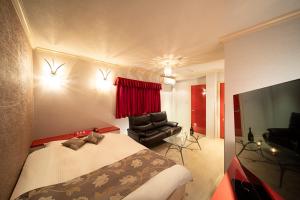 1 dormitorio con 1 cama, 1 silla y TV en ホテル リベラル 男塾ホテルグループ en Kobe