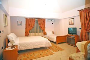a hotel room with two beds and a television at Hotel Primavera in Vlorë