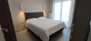 ein Schlafzimmer mit einem weißen Bett und einem Fenster in der Unterkunft AERIAL NEST in Thessaloniki