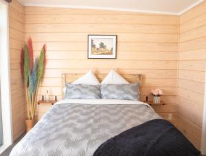 a bedroom with a bed and wooden walls at Bever Farm in Waitoki