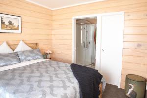 a bedroom with a bed and wooden walls at Bever Farm in Waitoki