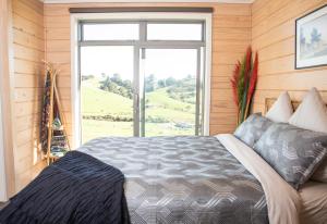 a bedroom with a bed with a large window at Bever Farm in Waitoki
