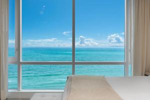 a bedroom with a large window looking out at the ocean at Oceanfront Private Condo at 1 Hotel & Homes -1219 in Miami Beach