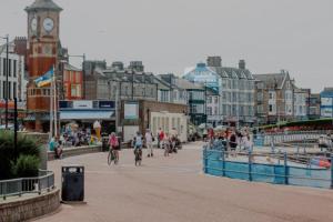 a group of people riding bikes down a street with a clock tower at 4 Bed house Sea Views Benji's by the beach in Morecambe