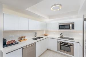 a white kitchen with white cabinets and a microwave at Luxurious Private Condo at 1 Hotel & Homes -1445 in Miami Beach