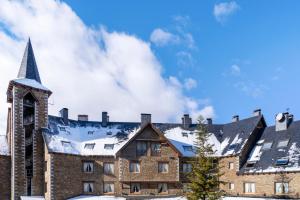a large brick building with snow on the roof at Eurostars La Pleta in Baqueira-Beret
