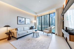 a living room with a couch and a tv at FAM Living - Burj Khalifa Bliss: Address Opera Modern 2BR in Dubai